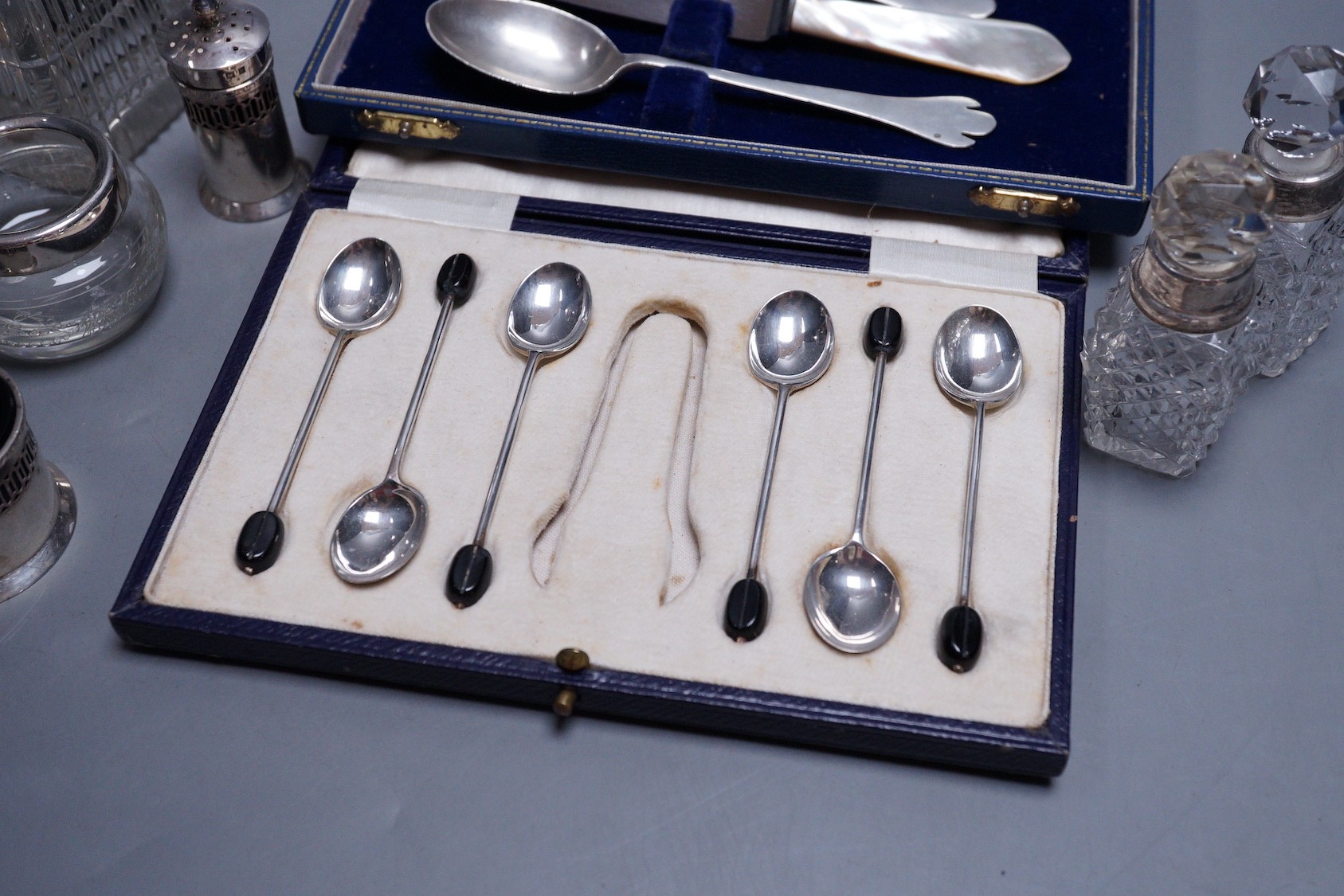 A modern 17th century style silver dog nose christening spoon and fork by Mappin & Webb, an associated knife, a cased set of six silver bean end coffee spoons (lacking tongs), a silver three piece condiment set and five